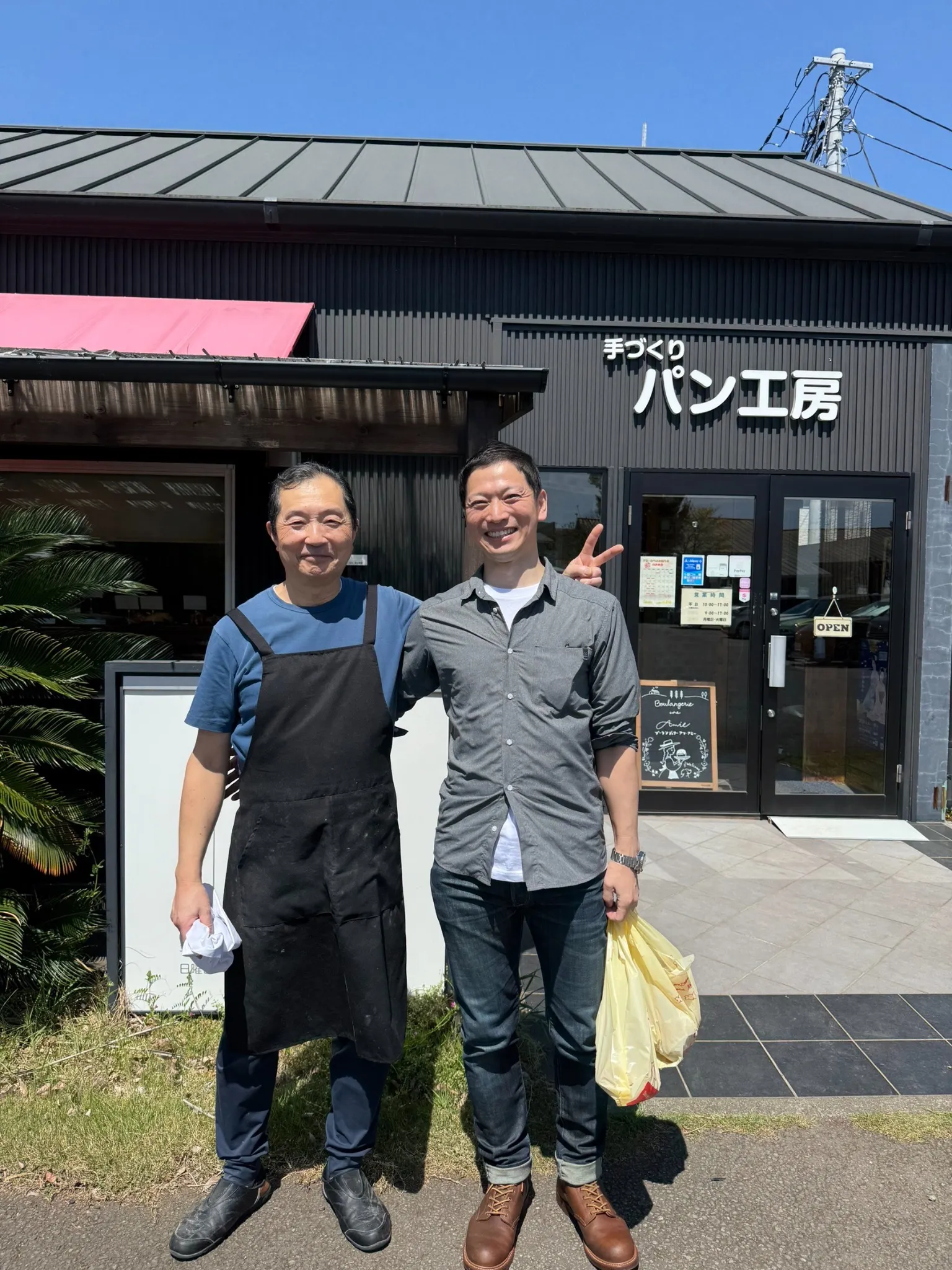 店の前に立つ、左の店主と右の以前の職場の後輩